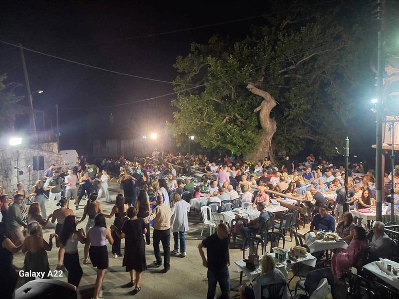 Θέα προς την πλατεία από το Ιατρείο. Η πλατεία είναι γεμάτη κόσμο και στον δρόμο χορεύουν.